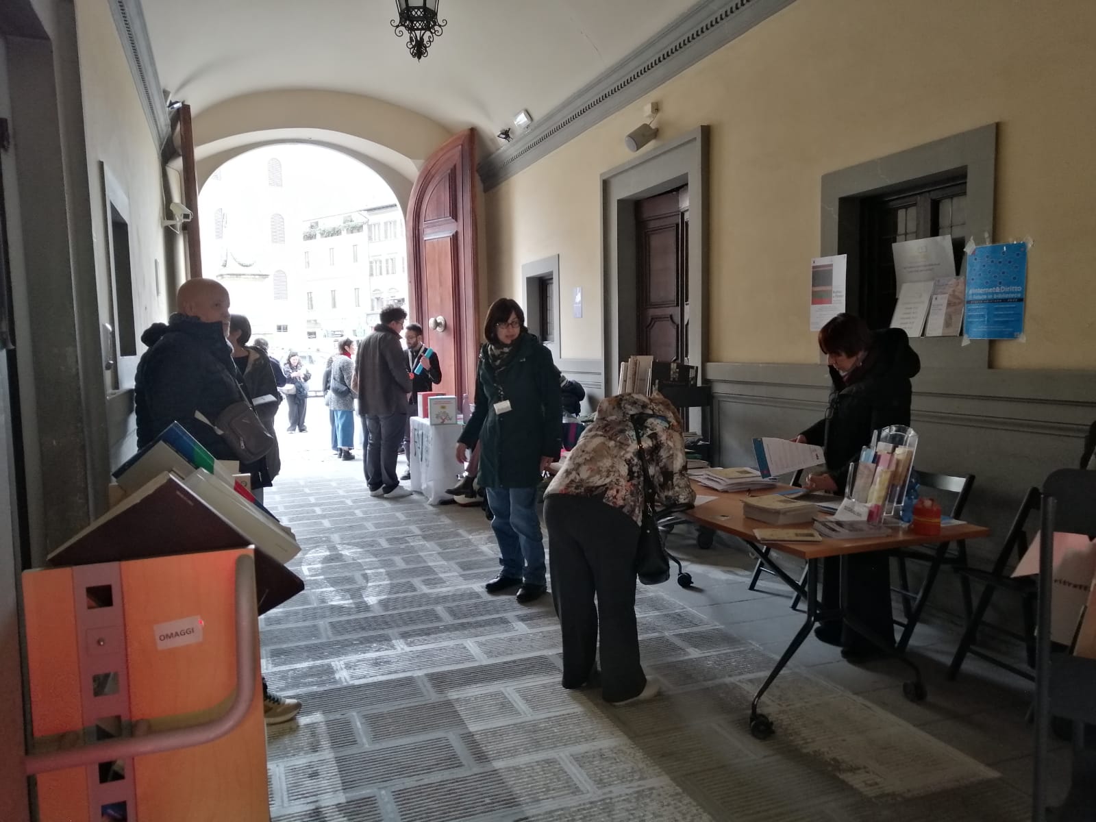 Androne del Palazzo Cerretani con personale della biblioteca e banchini allestiti con brochure, opuscoli sul palazzo e moduli di iscrizione